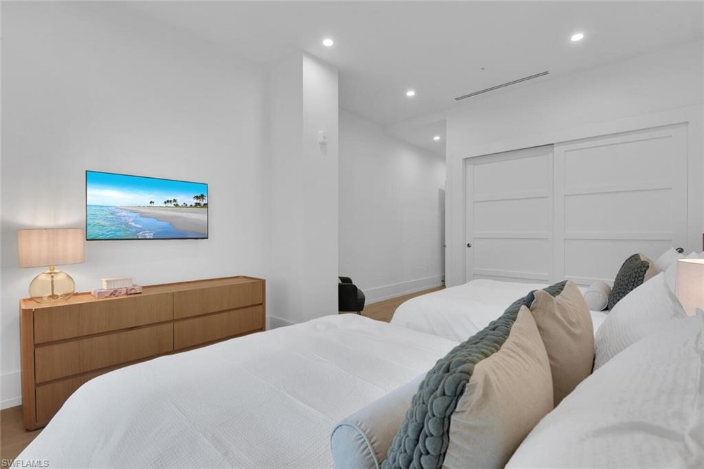 Bedroom featuring wood finished floors, baseboards, recessed lighting, and a closet