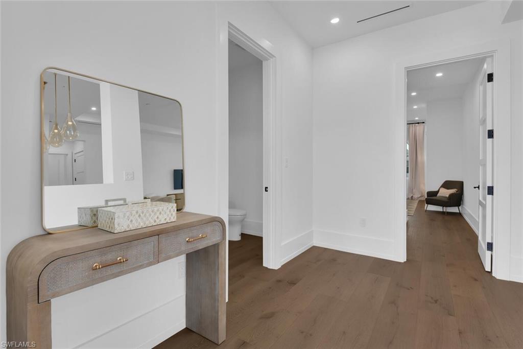 Corridor with wood finished floors, baseboards, and recessed lighting