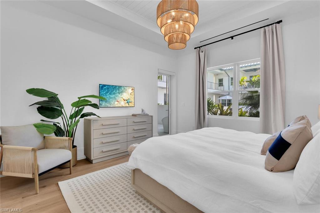 Bedroom with multiple windows, light wood-style floors, and a chandelier