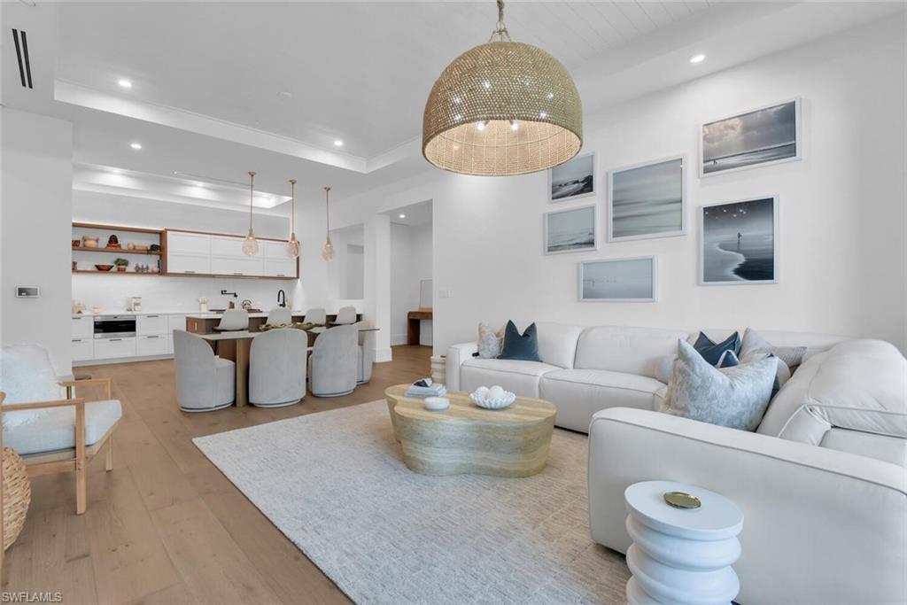 Living room with recessed lighting, light wood finished floors, crown molding, and a tray ceiling