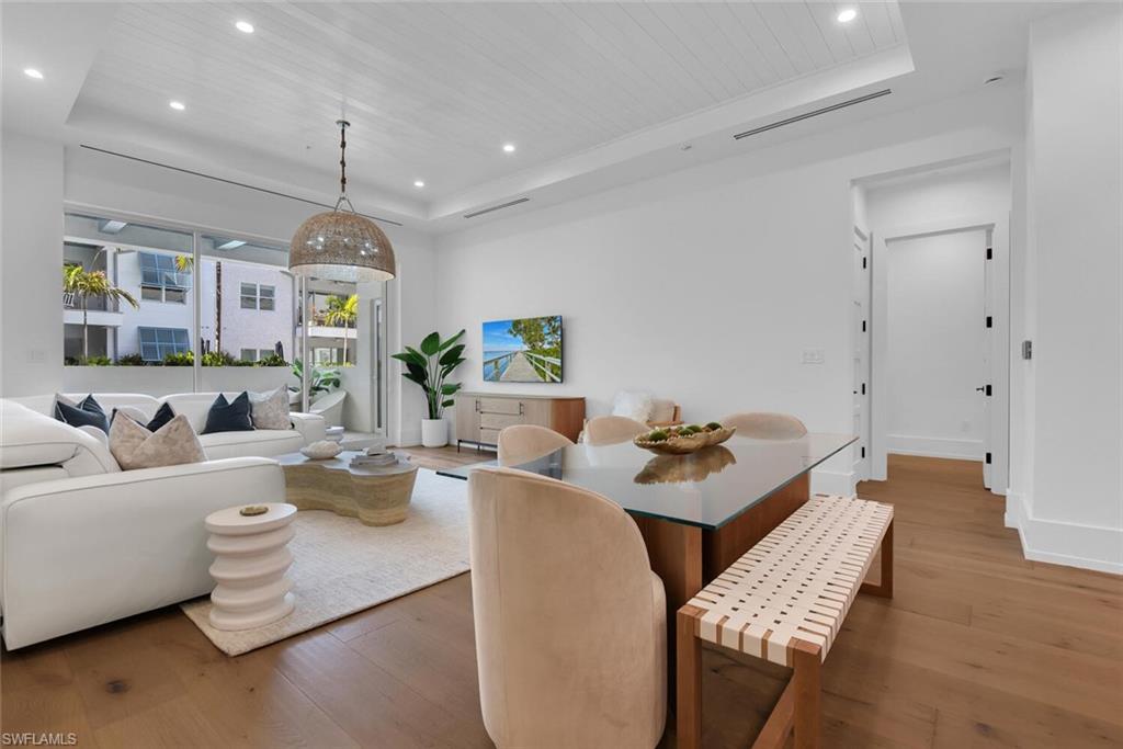 Dining room with a tray ceiling, wood finished floors, recessed lighting, wooden ceiling, and baseboards
