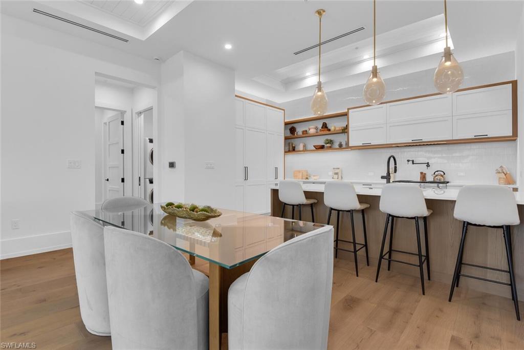 Dining space with light wood-type flooring, a raised ceiling, recessed lighting, and baseboards