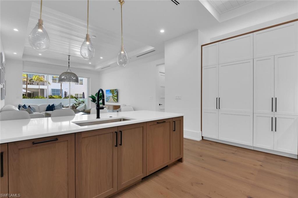 Kitchen featuring a sink, open floor plan, light wood-style floors, light countertops, and recessed lighting