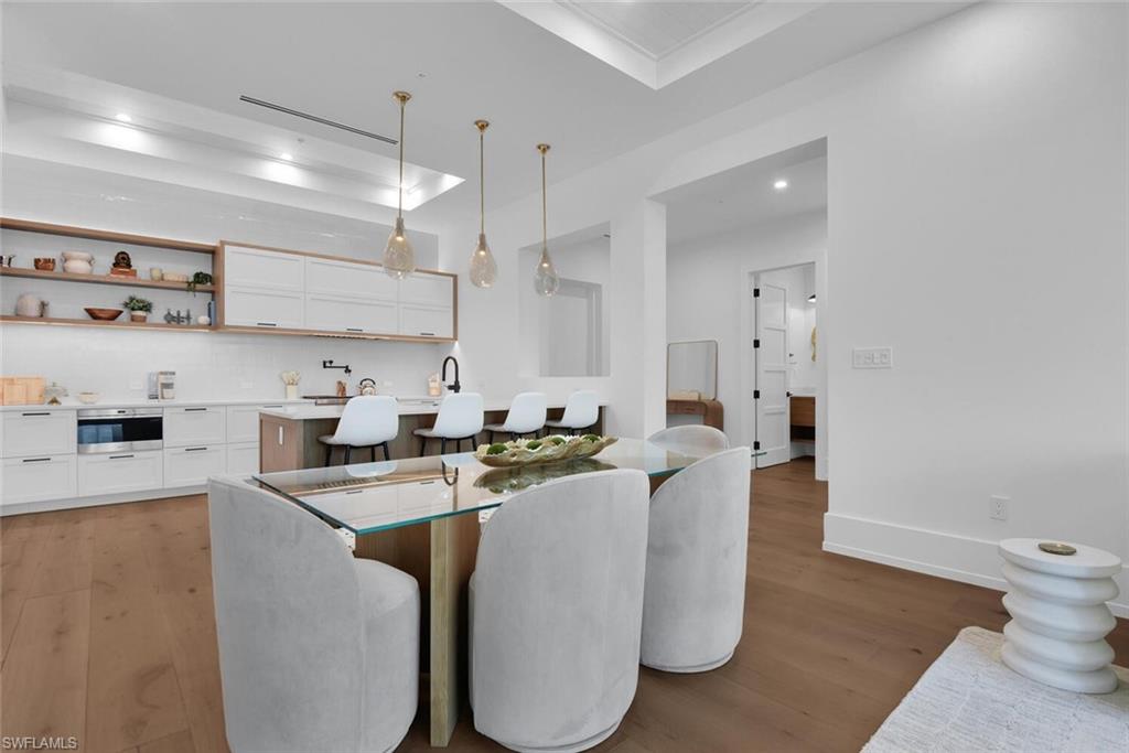 Dining space with light wood-style floors, a tray ceiling, recessed lighting, and baseboards