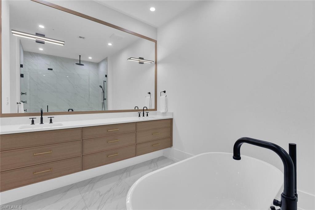 Full bath featuring marble finish floors, a marble finish shower, double vanity, recessed lighting, and a soaking tub