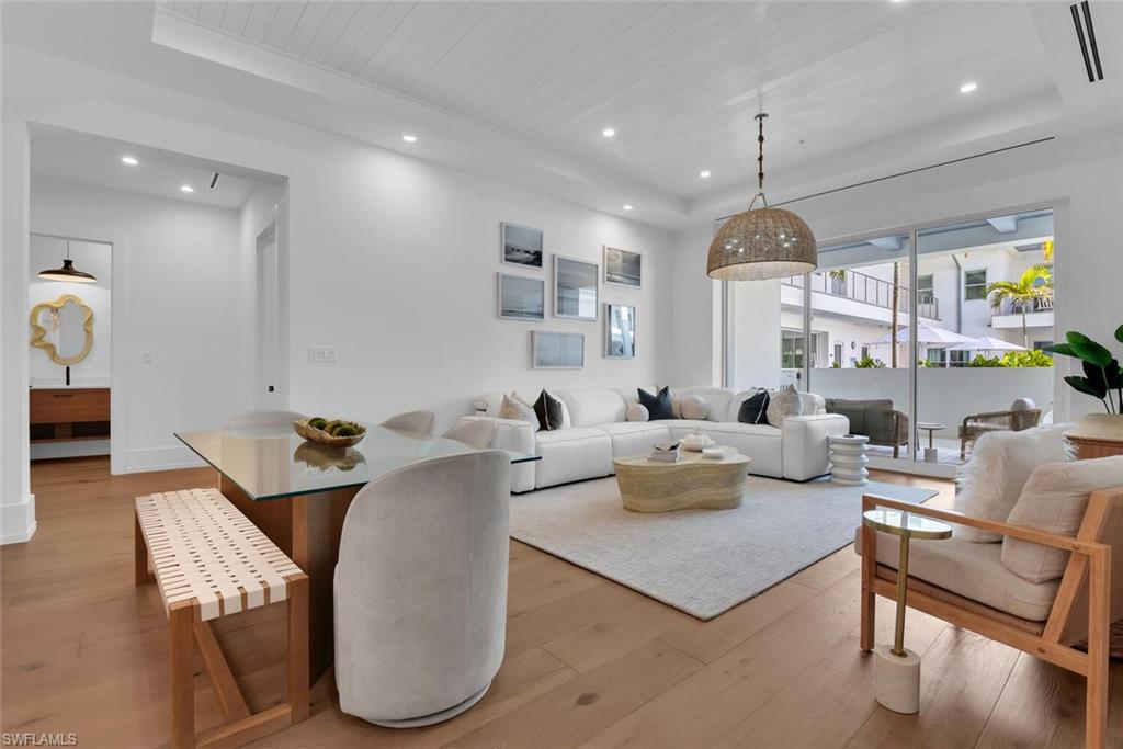 Living area with a tray ceiling, light wood finished floors, wooden ceiling, and recessed lighting