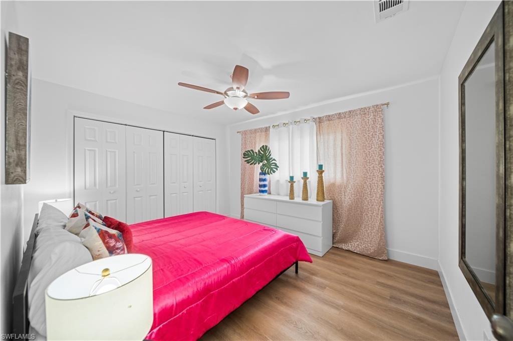 Bedroom featuring wood-finish flooring, white walls, and a ceiling fan with light fixture