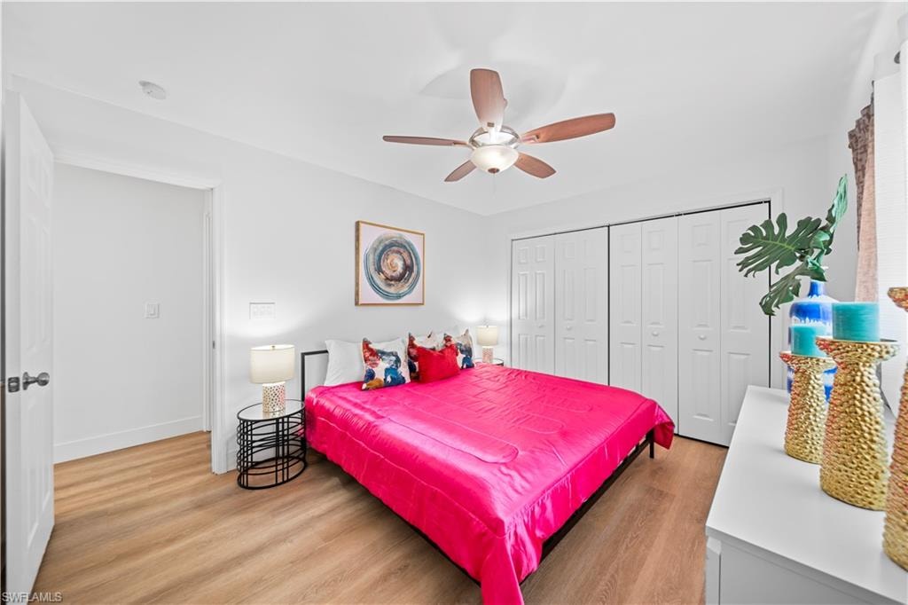 Bright interior space featuring light wood-finish flooring, a ceiling fan with integrated lighting, and multiple paneled bi-fold closet doors