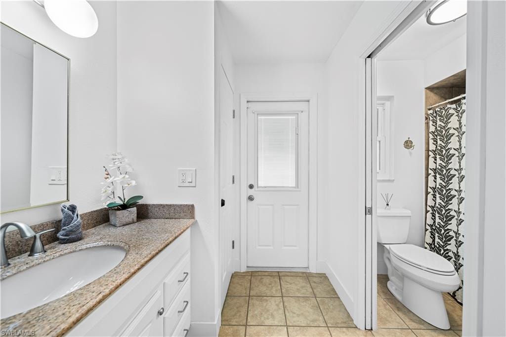 Bathroom featuring a single vanity with a granite-style countertop, white cabinetry with silver hardware, a recessed sink, and a wall-mounted mirror