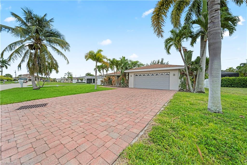 Brick paver driveway leading to a two-car garage with a panel door