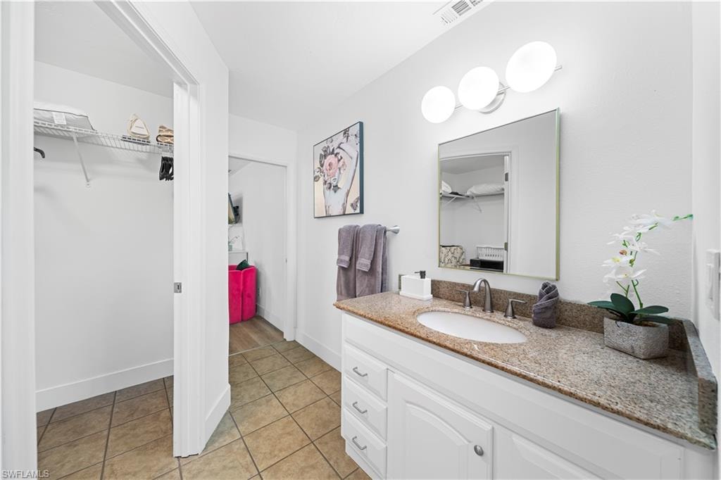 Bathroom vanity featuring a granite countertop, undermount sink, and brushed nickel faucet