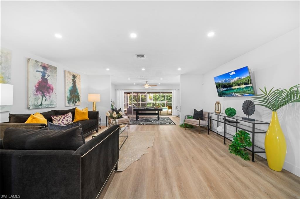 Open-concept living area with wood-finish flooring, recessed lighting, and white walls
