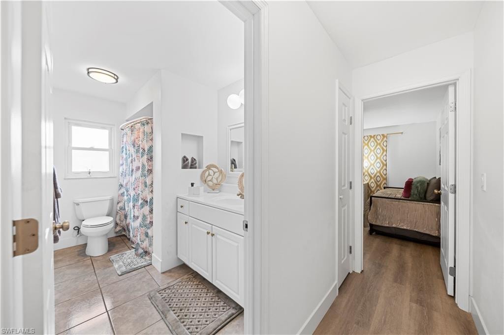Bright bathroom featuring a dual vanity with white cabinetry, tile flooring, and a tub/shower combination with a window