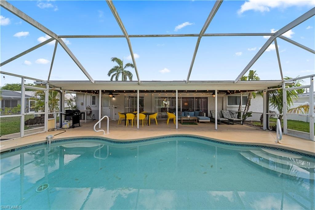Screened pool enclosure featuring an in-ground pool with steps, a covered patio, and concrete decking