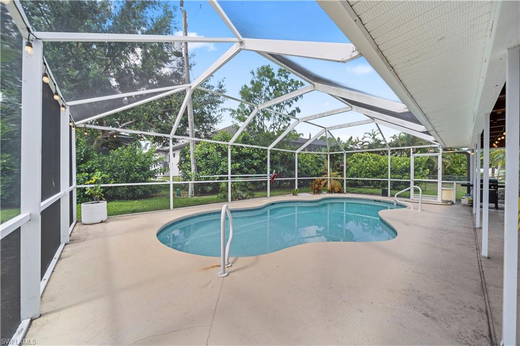 Screened-in outdoor pool area featuring a freeform pool, concrete deck, and covered patio space