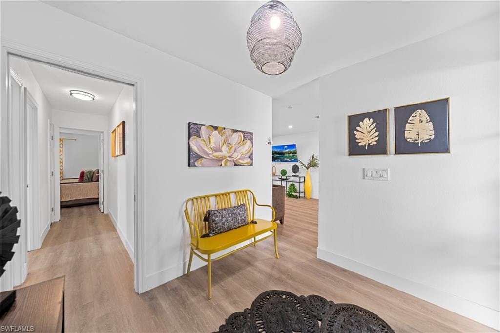Entryway featuring wood-finish flooring, white baseboards, and a woven pendant light fixture