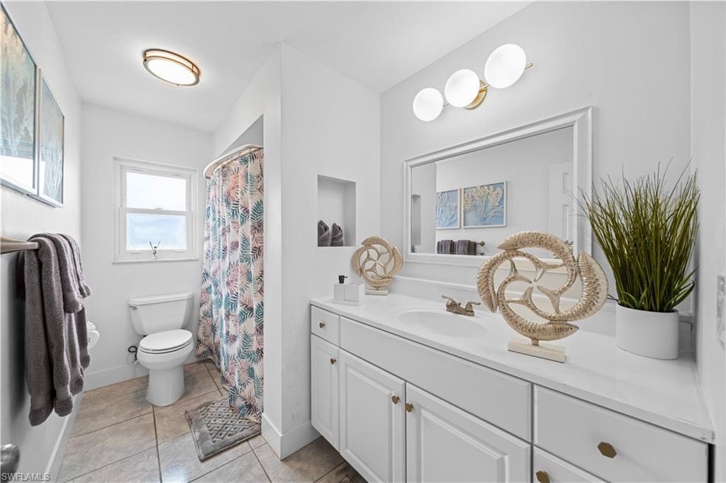 Bathroom featuring a single vanity with white cabinetry, a built-in sink, and a framed mirror