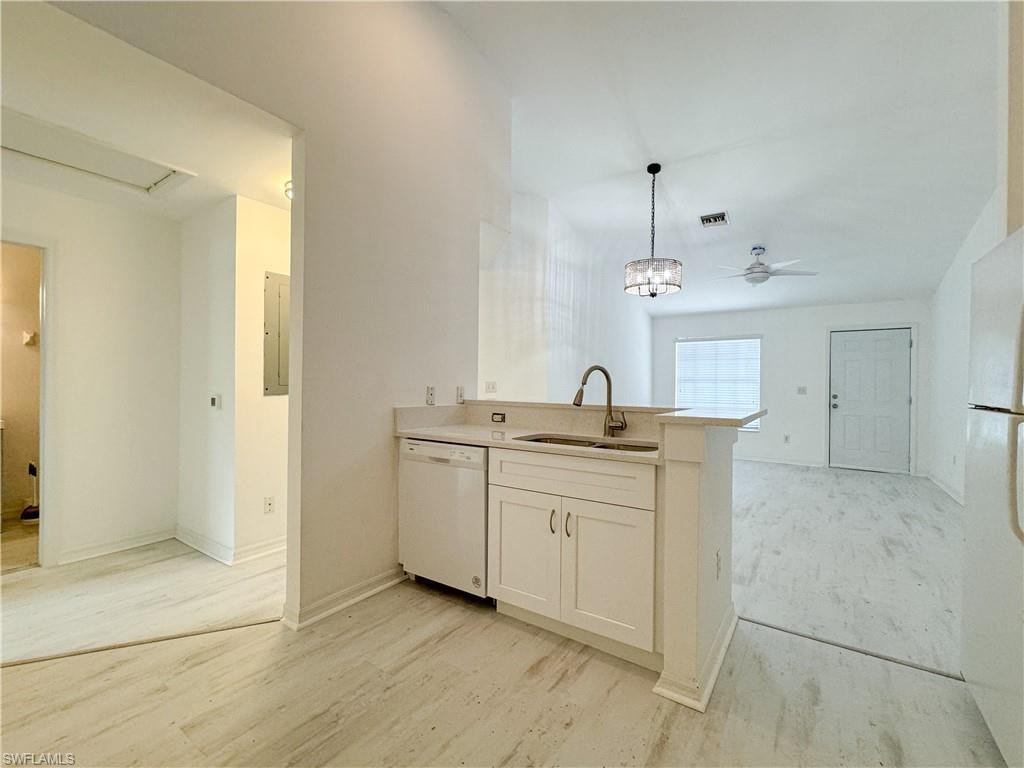 Kitchen featuring ceiling fan with notable chandelier, white cabinets, sink, kitchen peninsula, and white appliances
