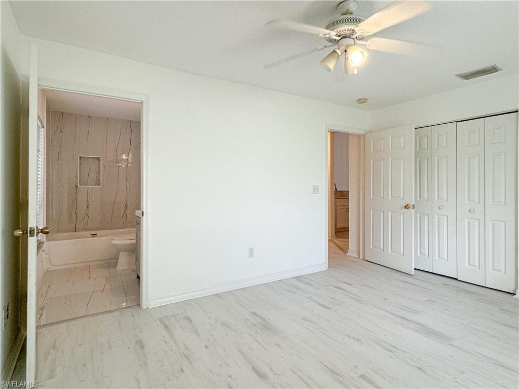 Unfurnished bedroom with ceiling fan, a closet, connected bathroom, and light hardwood / wood-style floors