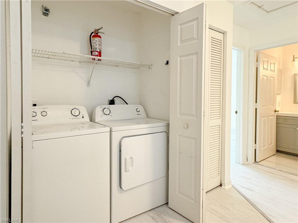 Laundry room with washing machine and dryer and light hardwood / wood-style flooring