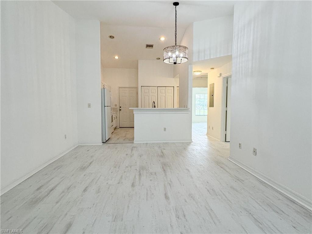 Unfurnished living room featuring light hardwood / wood-style flooring and a notable chandelier