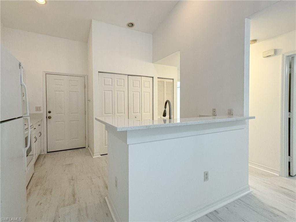 Kitchen featuring sink, kitchen peninsula, light hardwood / wood-style flooring, and white refrigerator