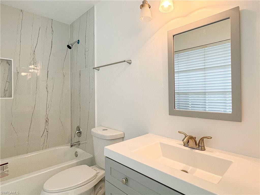 Full bathroom featuring tiled shower / bath, toilet, and vanity