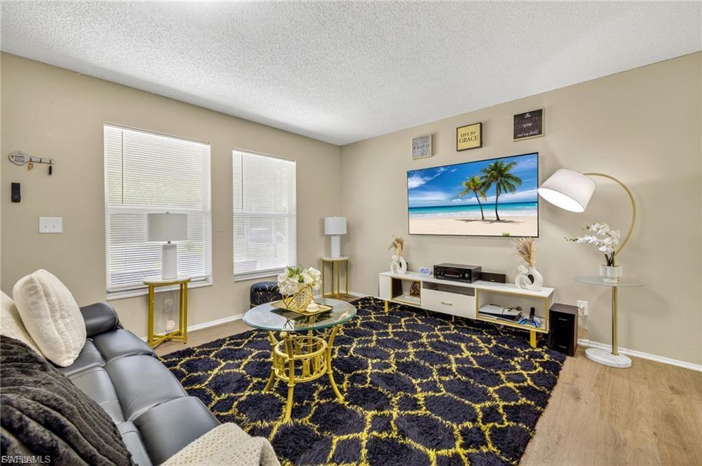 Living area featuring wood-finish flooring, neutral wall paint, and two windows with blinds
