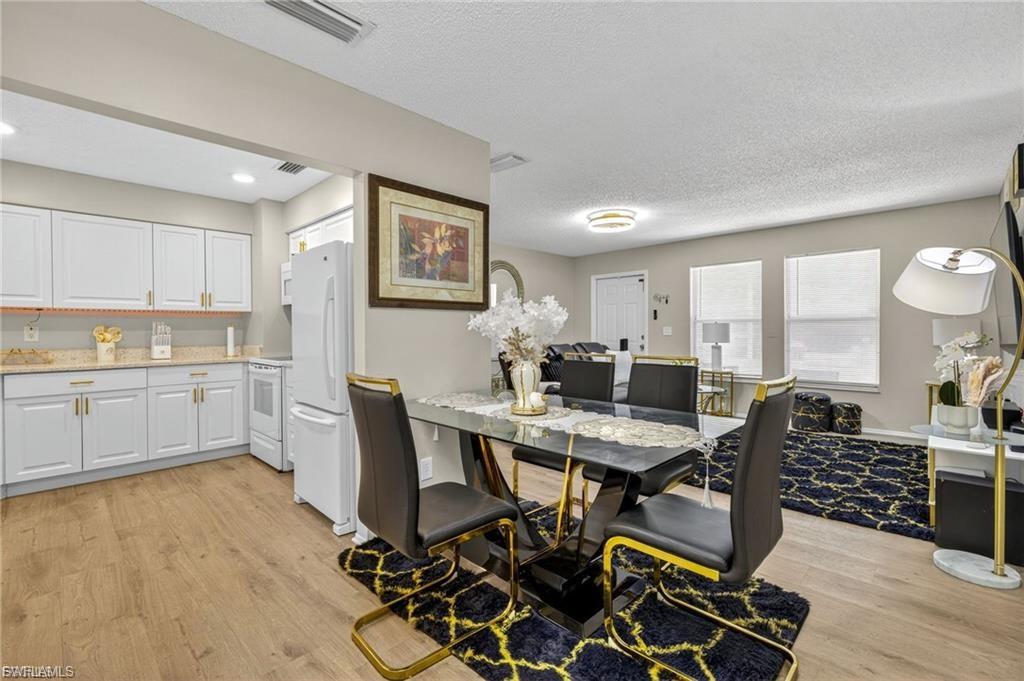 Open-concept living space featuring wood-finish flooring, recessed lighting, and a kitchen with white cabinetry and a light-toned countertop