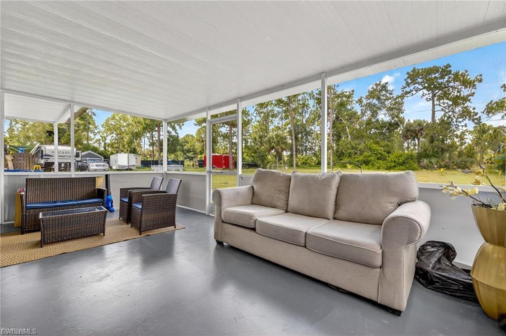 Screened outdoor living area featuring a solid ceiling, painted concrete flooring, and surrounding natural landscaping