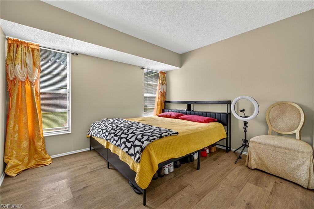 Interior space featuring wood-finish flooring, two window openings with blinds, and neutral wall tones
