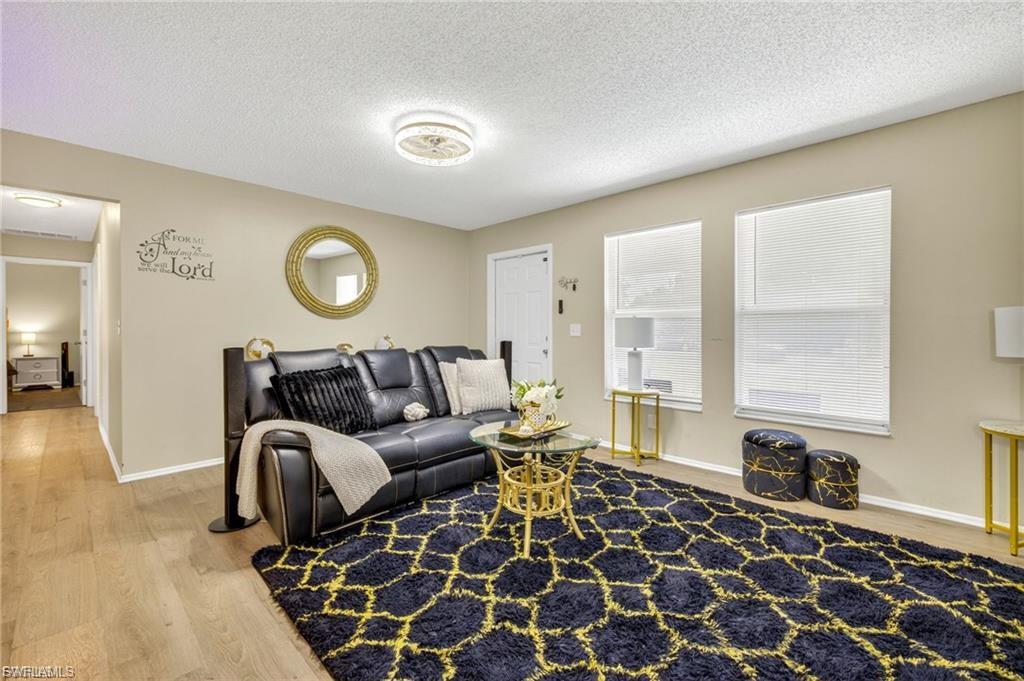 Living area featuring wood-finish flooring, neutral wall tones, and multiple windows with blinds