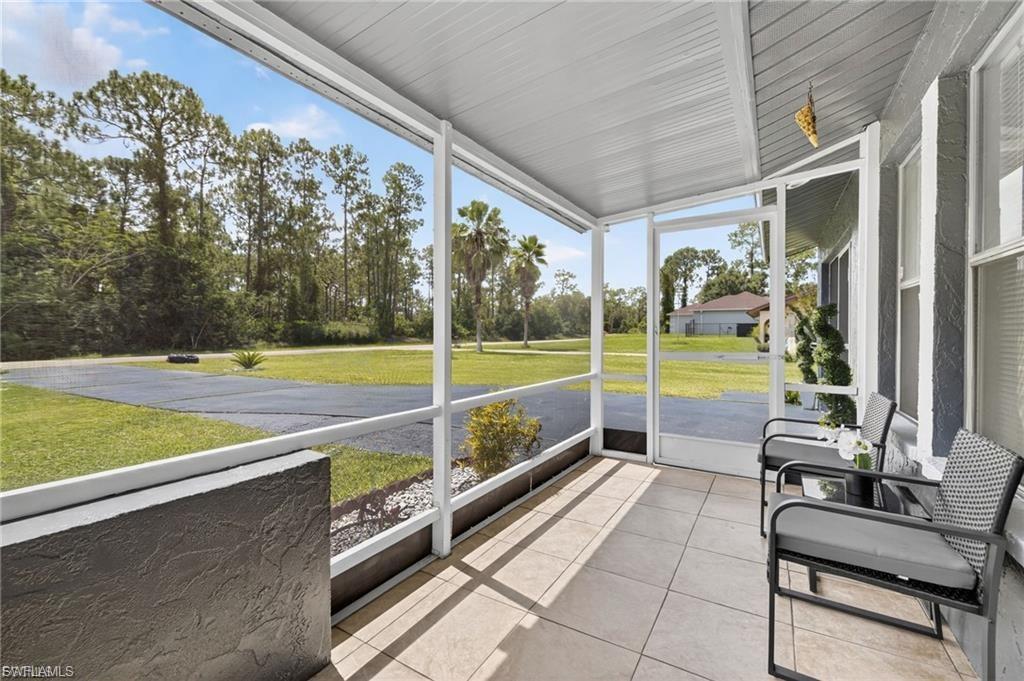 Screened lanai featuring large format tile flooring, a textured exterior wall, and a white aluminum frame