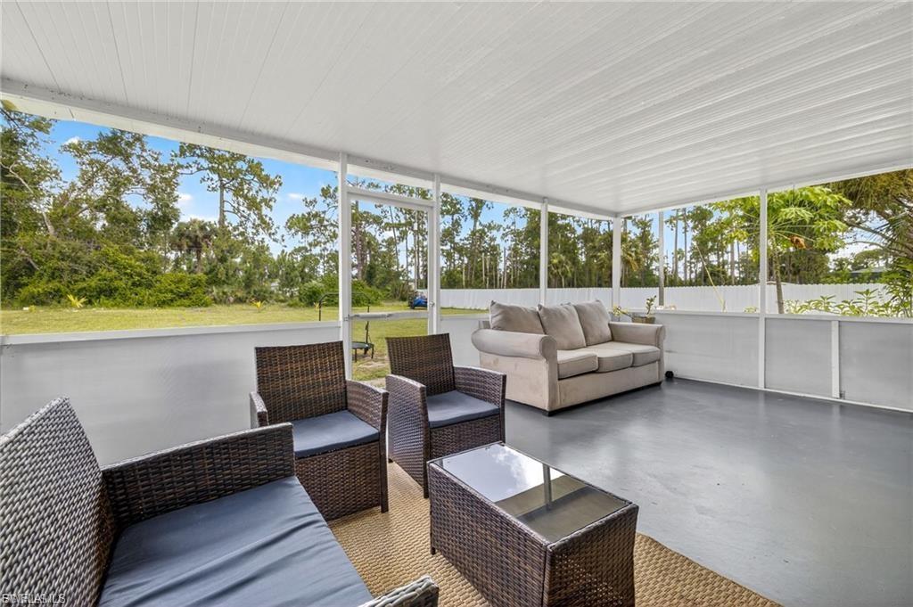 Expansive screened patio featuring a solid roof, a concrete floor, and a surrounding privacy wall