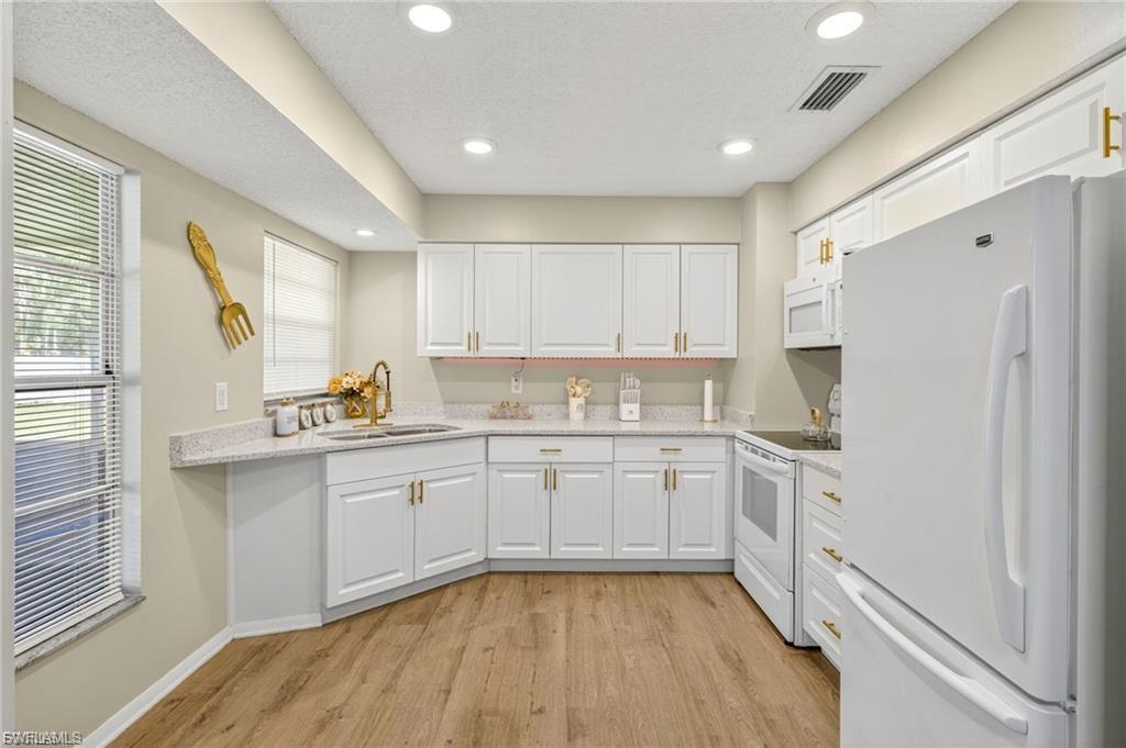 Kitchen featuring white cabinetry, light-colored countertops, and wood-finish flooring