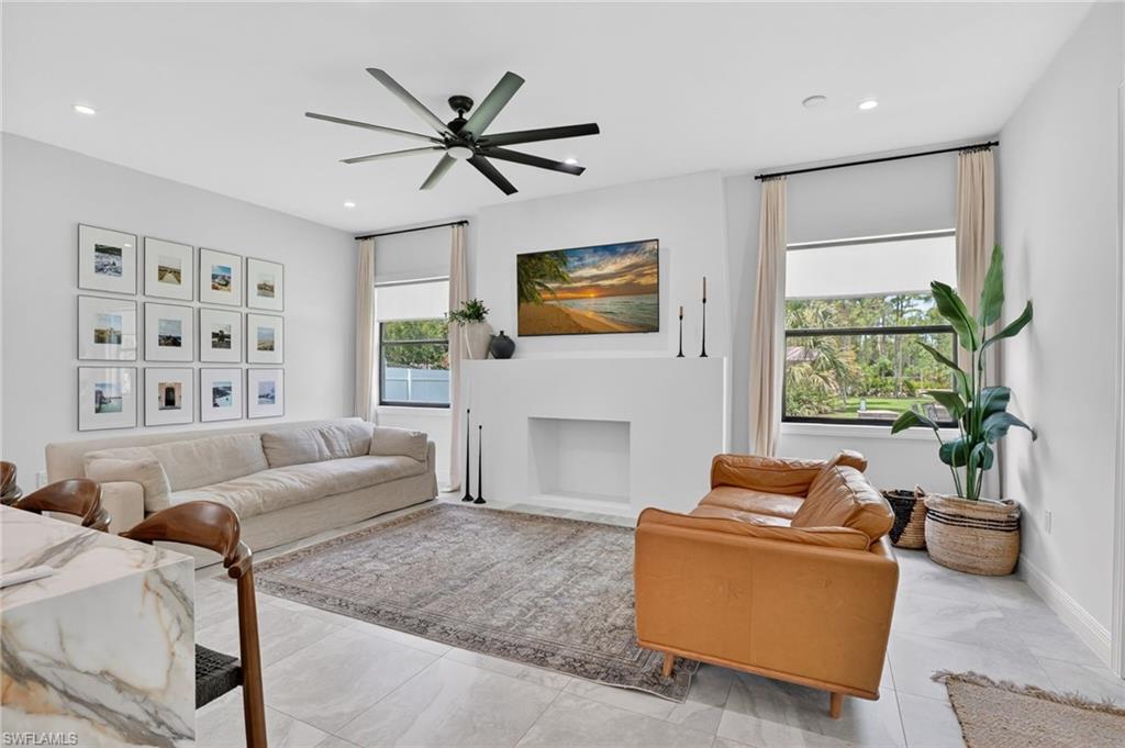 Spacious living area featuring large format tile flooring, a modern ceiling fan, and a built-in fireplace structure