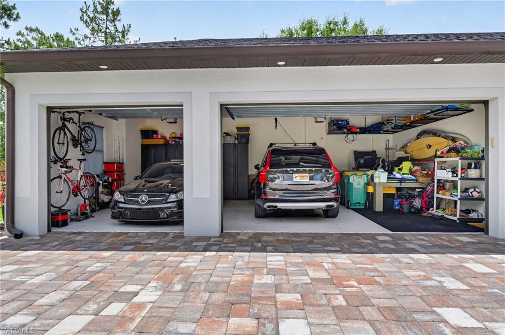 Two-car garage featuring individual bay doors, a comprehensive storage system, and a paved brick driveway
