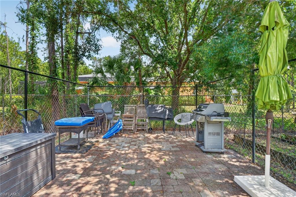 Paved patio area featuring brick-patterned pavers and a chain-link fence