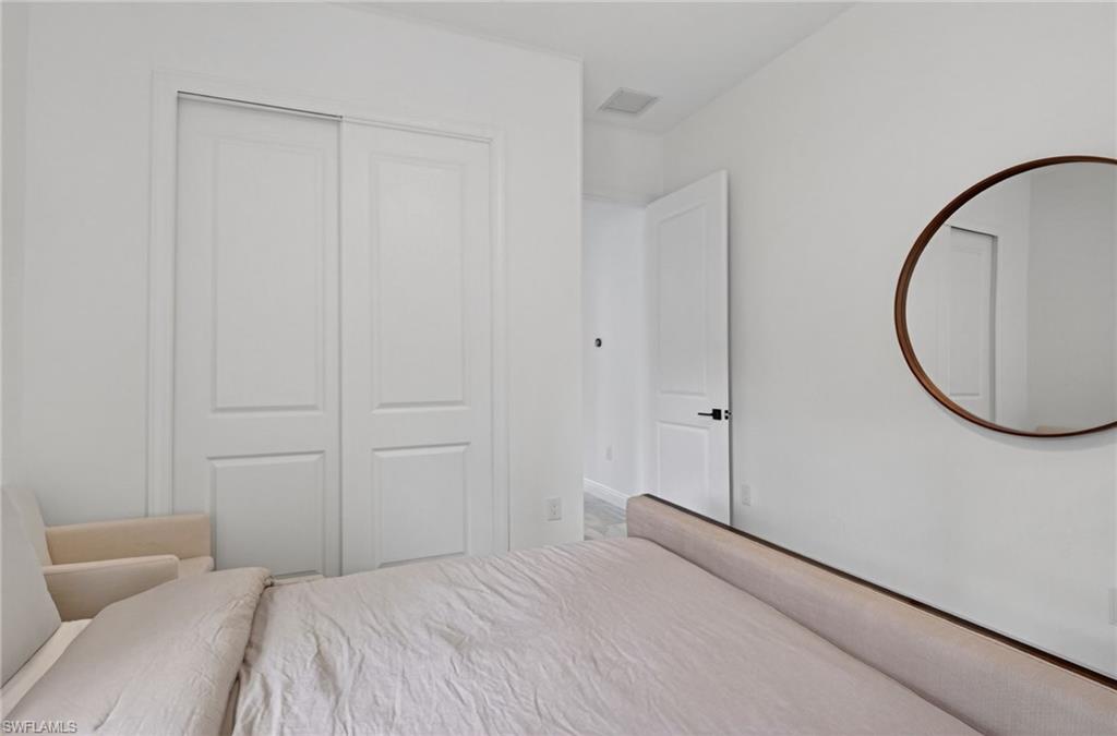 White interior room featuring a two-panel sliding closet door, white trim, and a contemporary round wall mirror