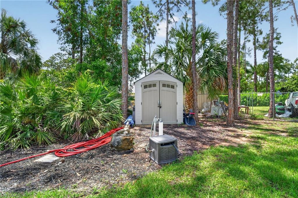 Freestanding shed with double arched doors, set amidst mature trees and tropical landscaping