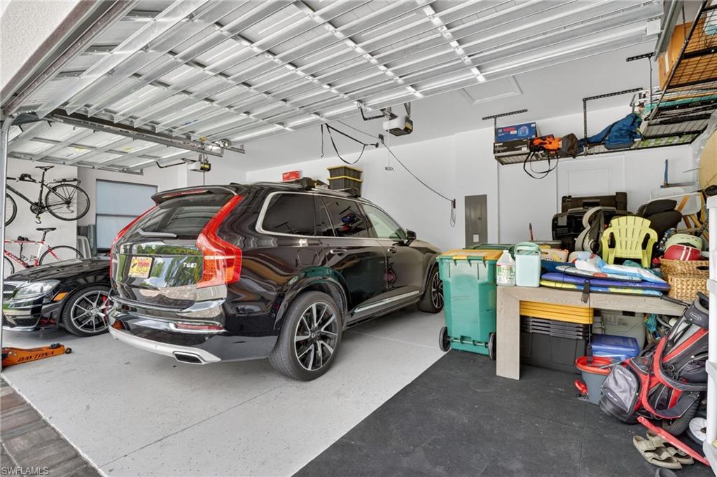 Spacious two-car garage featuring a sectional garage door, light-colored flooring, white walls, and integrated overhead storage racks