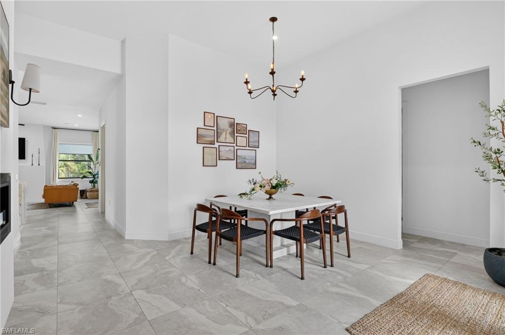 Spacious dining area featuring a modern chandelier, light-toned flooring, and crisp white walls