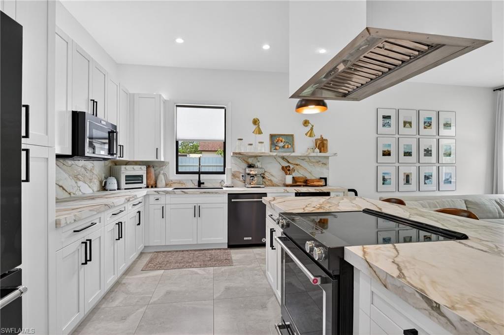 Modern kitchen featuring white cabinetry, integrated black appliances, and veined stone countertops
