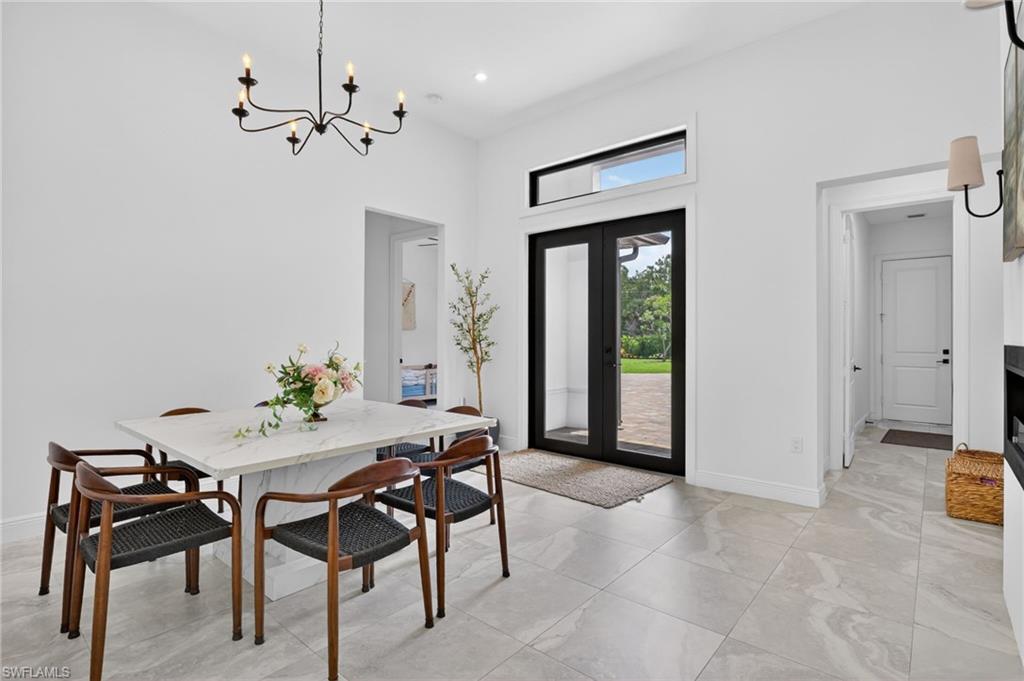 Spacious entry area with light-toned tile flooring, double glass panel doors, and a transom window