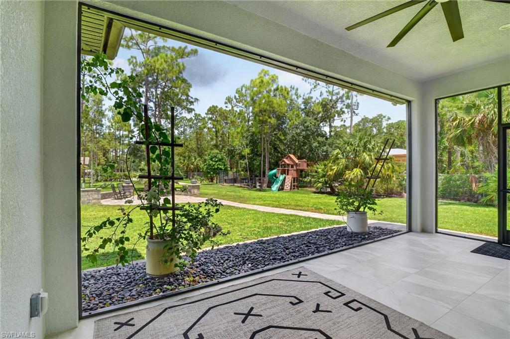 Screened patio with light-toned tile flooring, dark pebble accents, and a ceiling fan