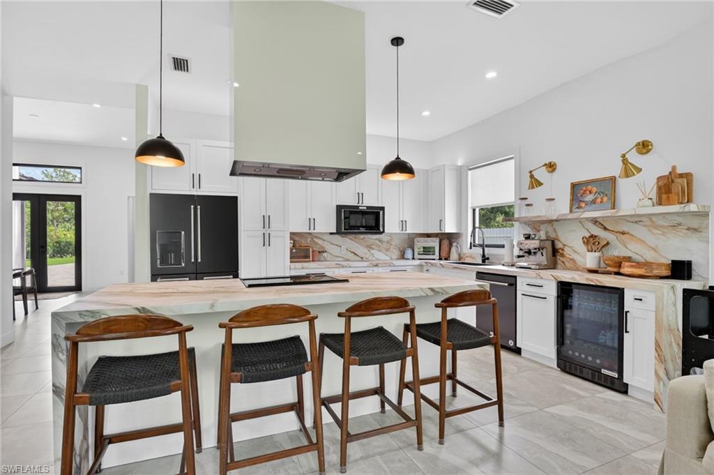 Gourmet kitchen with waterfall island, custom cabinetry, integrated range hood, and premium appliances