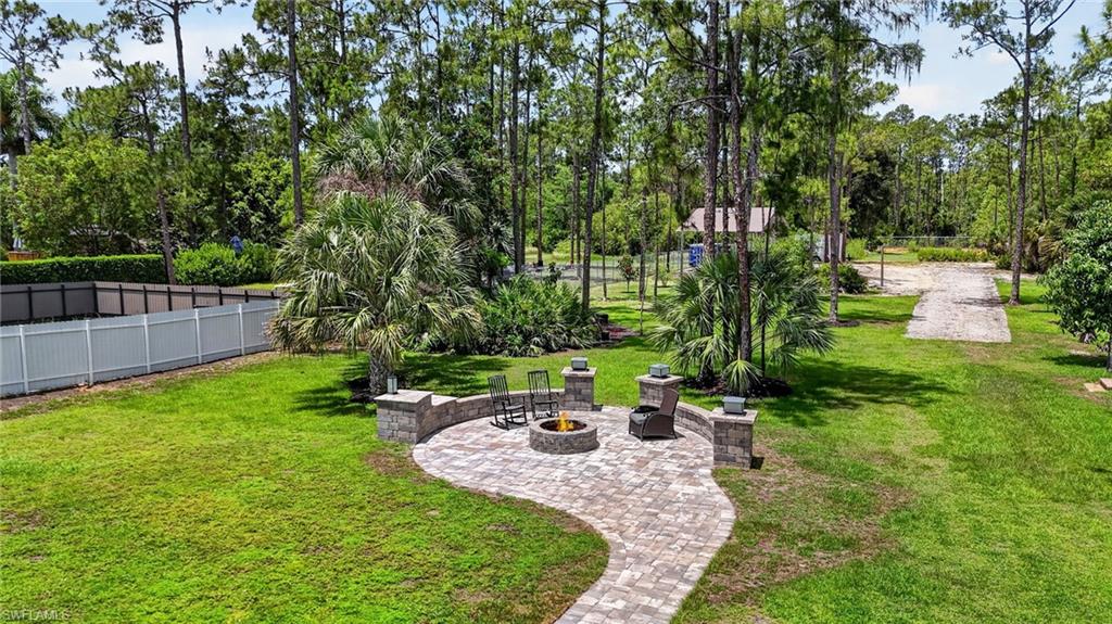 Expansive outdoor living area featuring a paver patio with a built-in fire pit, stone accent walls, and a stone-clad fire feature