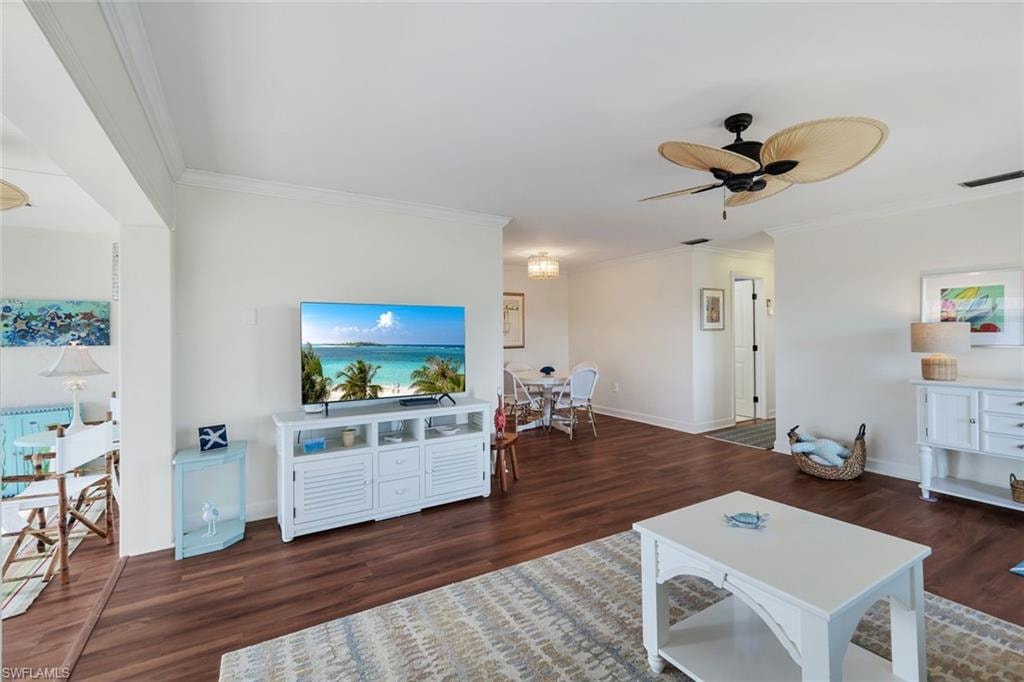Open-concept living space with crown molding, wood-finish flooring, and a ceiling fan