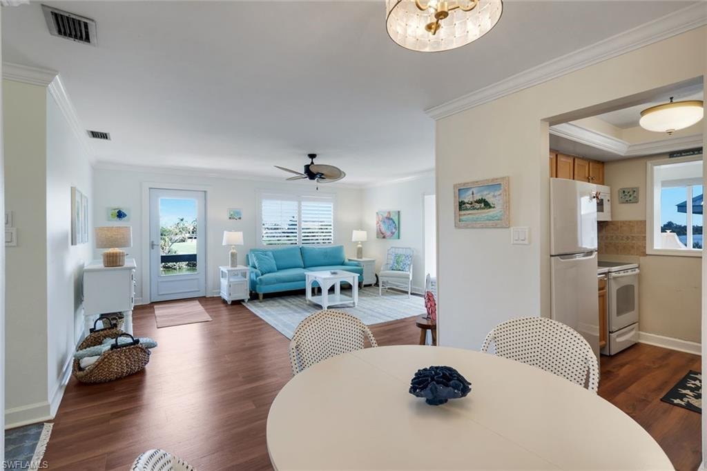 Open-concept living area featuring wood-finish flooring, a ceiling fan, and crown molding