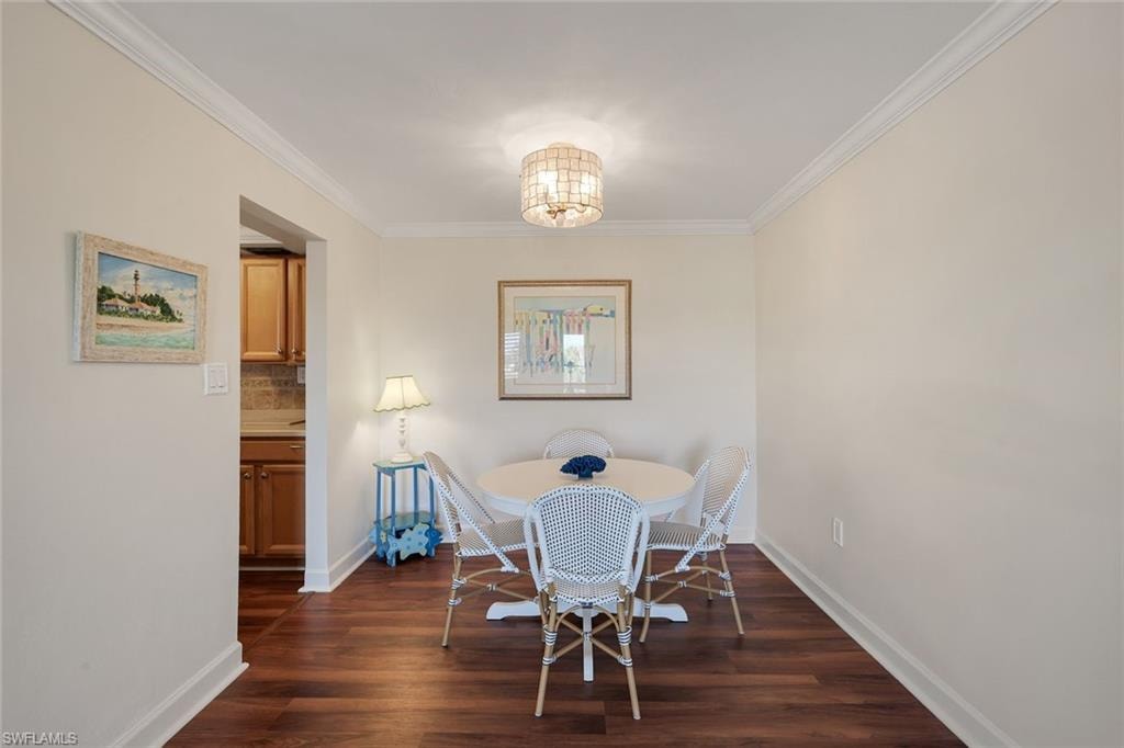 Dining area featuring wood-finish flooring, crown molding, and a drum pendant light fixture